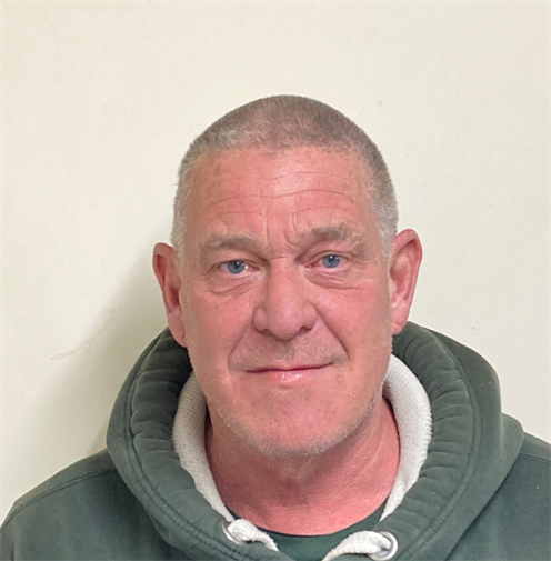 Photograph of a man with a shaved head wearing a dark green hoodie. Photograph of a man with a shaved head wearing a dark green hoodie.